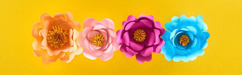 flat lay with paper cut multicolored bright flowers on yellow background, panoramic shot