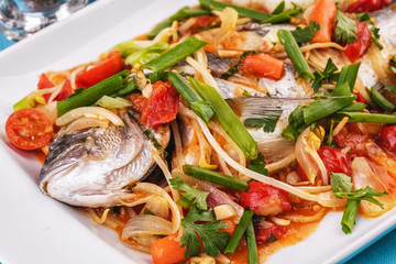 Seafood, Mediterranean cuisine. Baked sea fish with mushrooms, herbs, carrots, millers, cilantro, corn and onions. Caucasian national cuisine