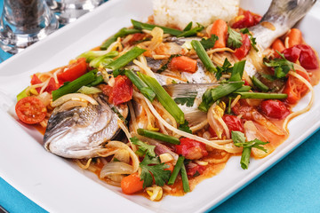 Seafood, Mediterranean cuisine. Baked sea fish with mushrooms, herbs, carrots, millers, cilantro, corn and onions. Caucasian national cuisine