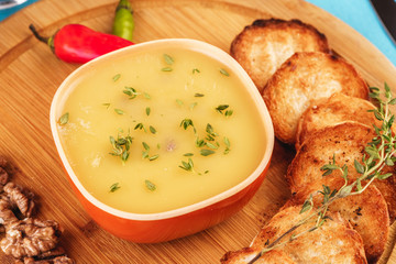 Mediterranean dish, European cuisine. Fish and cream cheese soup with herbs, garlic bread, red and green chili peppers, thyme and walnuts