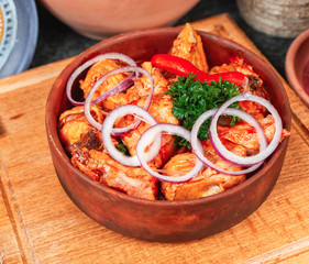 goulash from chicken pieces and vegetables, served with greens, red pepper and onion rings...