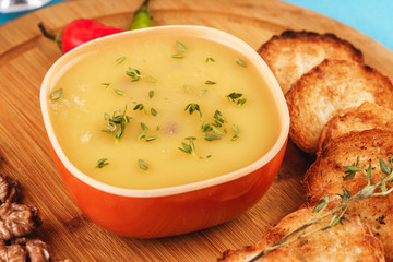 Mediterranean dish, European cuisine. Fish and cream cheese soup with herbs, garlic bread, red and green chili peppers, thyme and walnuts