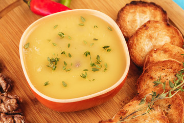 Mediterranean dish, European cuisine. Fish and cream cheese soup with herbs, garlic bread, red and green chili peppers, thyme and walnuts