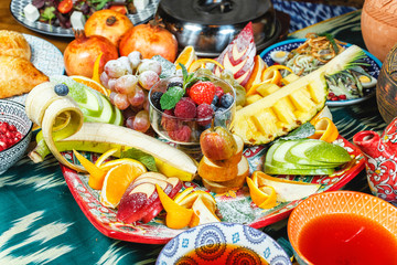 Fruit plate in oriental style according to the Uzbek recipe. Strawberries, raspberries, blackberries, pineapple, orange, apple, pear, grapes, banana, blueberries, pomegranate, grapefruit with powdered