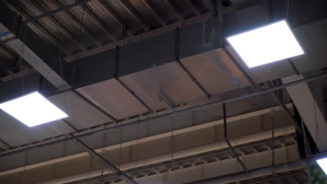 long pipes of industrial hvac system and lamps on ceiling of big shopping center