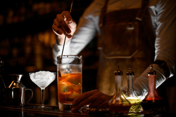 Bartender stirring alcohol cocktail with the spoon