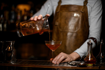 Bartender pours alcohol cocktail with a strainer