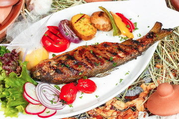 Mediterranean dish, Georgian recipe. Baked river fish with lemon, vegetables, pepper and grilled...