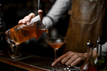 Bartender pours an alcohol cocktail from strainer