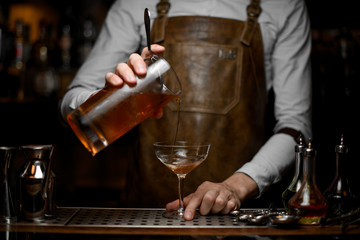 Bartender pours alcohol cocktail from a strainer