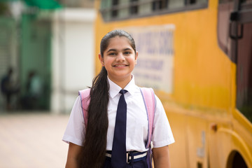 Portrait of schoolgirl in uniform with bag and water bottle