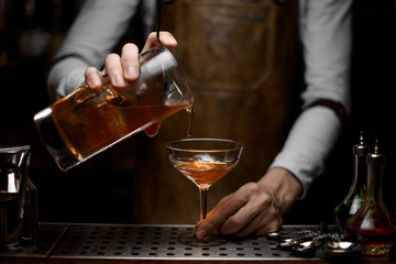Bartender pouring an alcohol cocktail with strainer