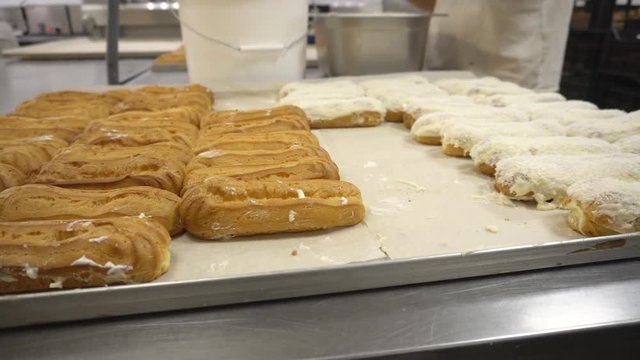 Making and decorating custard cakes with the help of glaze and coconut chips at a confectionery factory, handwork