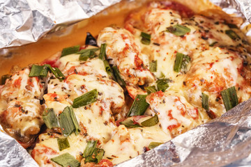 Seafood, Mediterranean cuisine, European dish. Fish baked in a foil with tomatoes, entirely with onion rings, red and green peppers, chili peppers, greens, cheese, mushrooms and vegetables. Caucasian 