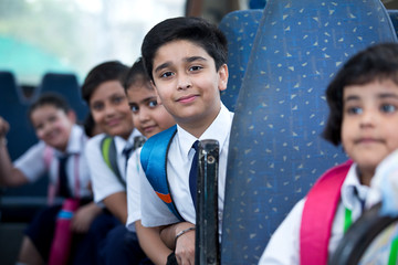 School children traveling in school bus looking at camera