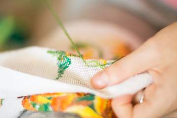  The process of working embroidery. Hands girls embroider pattern of flowers. Embroidery and cross stitch accessories. Close-up.