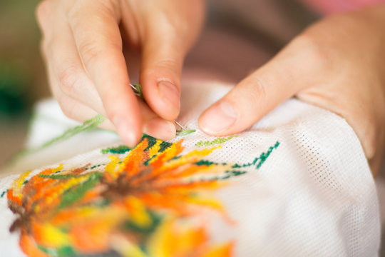  The process of working embroidery. Hands girls embroider pattern of flowers. Embroidery and cross stitch accessories. Close-up.