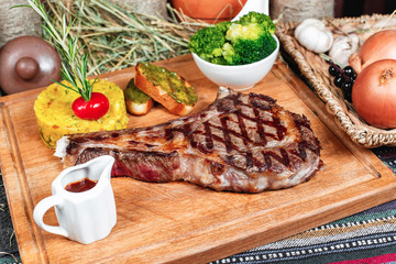 T bon steak fried on charcoal. Grilled meat with mashed potatoes, broccoli, tomato sauce and croutons in oriental style, Georgian appetizer. National cuisine