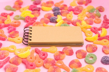 Coral paper background with sweets and blank notepad. Place for your text. Cozy sweet background