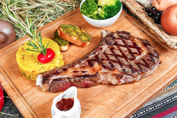 T bon steak fried on charcoal. Grilled meat with mashed potatoes, broccoli, tomato sauce and croutons in oriental style, Georgian appetizer. National cuisine