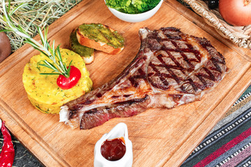 T bon steak fried on charcoal. Grilled meat with mashed potatoes, broccoli, tomato sauce and croutons in oriental style, Georgian appetizer. National cuisine
