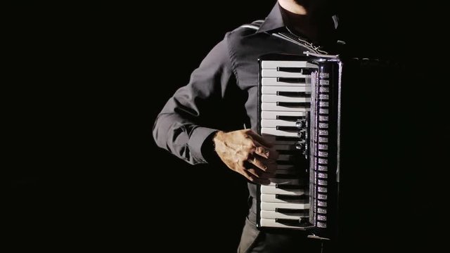 young musician virtuoso plays the accordion masterly in the studio on a black background,isolated,close-up