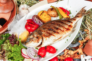 Baked trout fish Georgian recipe with pepper, onion, grilled vegetables and fresh lettuce, dressed with olive oil and spices. National cuisine