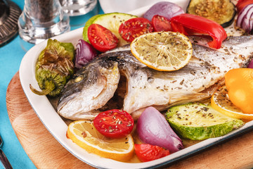 Mediterranean dish, Georgian recipe. Baked river fish with lemon, vegetables, pepper and grilled tomatoes with spices.