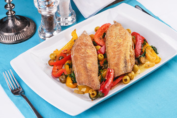 Grilled fish steak carp served with stewed chili peppers, olives, olives, greens and green pepper according to the Georgian recipe. Mediterranean Kitchen 