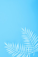 top view of paper leaves on blue minimalistic background with copy space