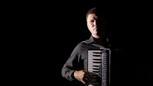 young musician virtuoso plays the accordion masterly in the studio on a black background,isolated,close-up
