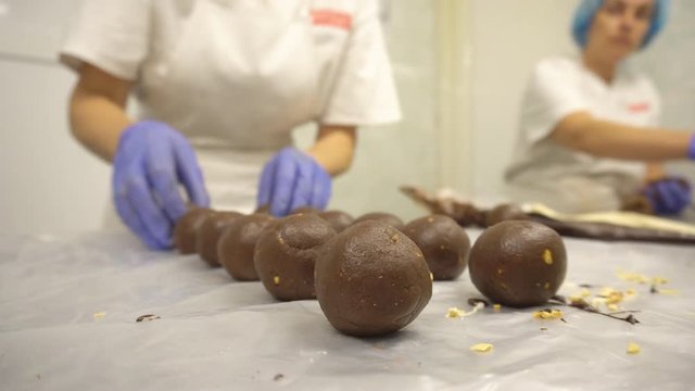 Decorating and making chocolate round cakes from kako. Women make cakes at a confectionery factory. Decorating sweets with cream and nuts, food industry