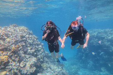 Man in snorkeling mask and suit dive underwater with tropical fishes in coral reef sea pool. Couple is swiming under the sea water. Travel lifestyle, water sport outdoor adventure concept.