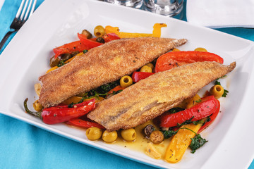Grilled fish steak carp served with stewed chili peppers, olives, olives, greens and green pepper according to the Georgian recipe. Mediterranean Kitchen 
