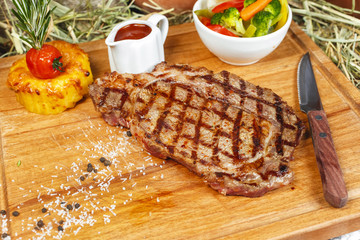 grilled beef steak according to Georgian recipe. Served with tomato sauce and fresh vegetable salad. National cuisine