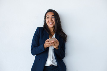 Cheerful businesswoman using mobile phone. Beautiful happy young businesswoman using smartphone isolated on grey background. Technology concept