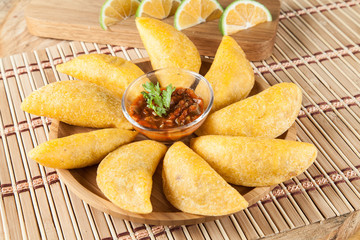 Tasty colombian food, fried empanada; photo on wooden background.