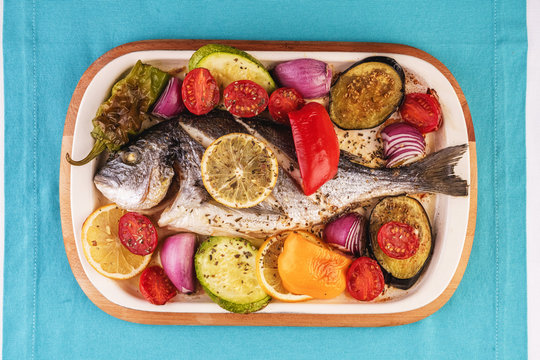 Mediterranean dish, Georgian recipe. Baked river fish with lemon, vegetables, pepper and grilled tomatoes with spices.