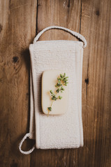 Washcloth with  soap with herb  on wooden  background.