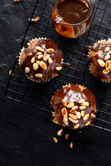 Nut-chocolate muffins covered with dark chocolate and roasted pine nuts, top view, close-up. Tasty breakfast or dessert