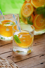 Orange infused water in glass on wooden table.