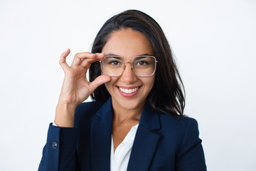 Content businesswoman adjusting eyeglasses. Portrait of beautiful young businesswoman wearing eyeglasses and smiling at camera. Business concept