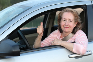 Cute mature female driver giving a thumbs up