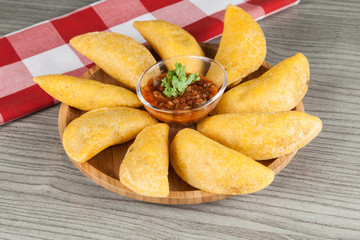 Tasty colombian food, fried empanada; photo on wooden background.