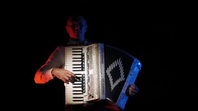 young accordionist plays the accordion masterly in the studio on a black background, isolated