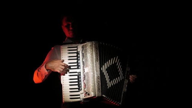 young accordionist plays the accordion masterly in the studio on a black background, isolated