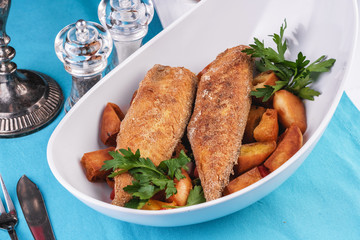 Grilled fish steak is served in batter with braised and roasted potato wedges. Mediterranean cuisine, European dish