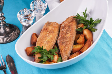 Grilled fish steak is served in batter with braised and roasted potato wedges. Mediterranean cuisine, European dish