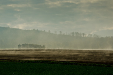 Morgendliche Nebelschwaden steigen aus Feldern auf und lösen sich in der  Morgensonne auf