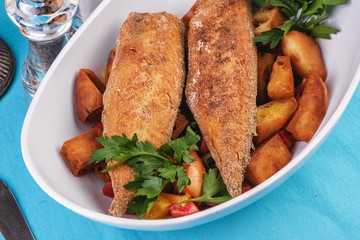 Grilled fish steak is served in batter with braised and roasted potato wedges. Mediterranean cuisine, European dish